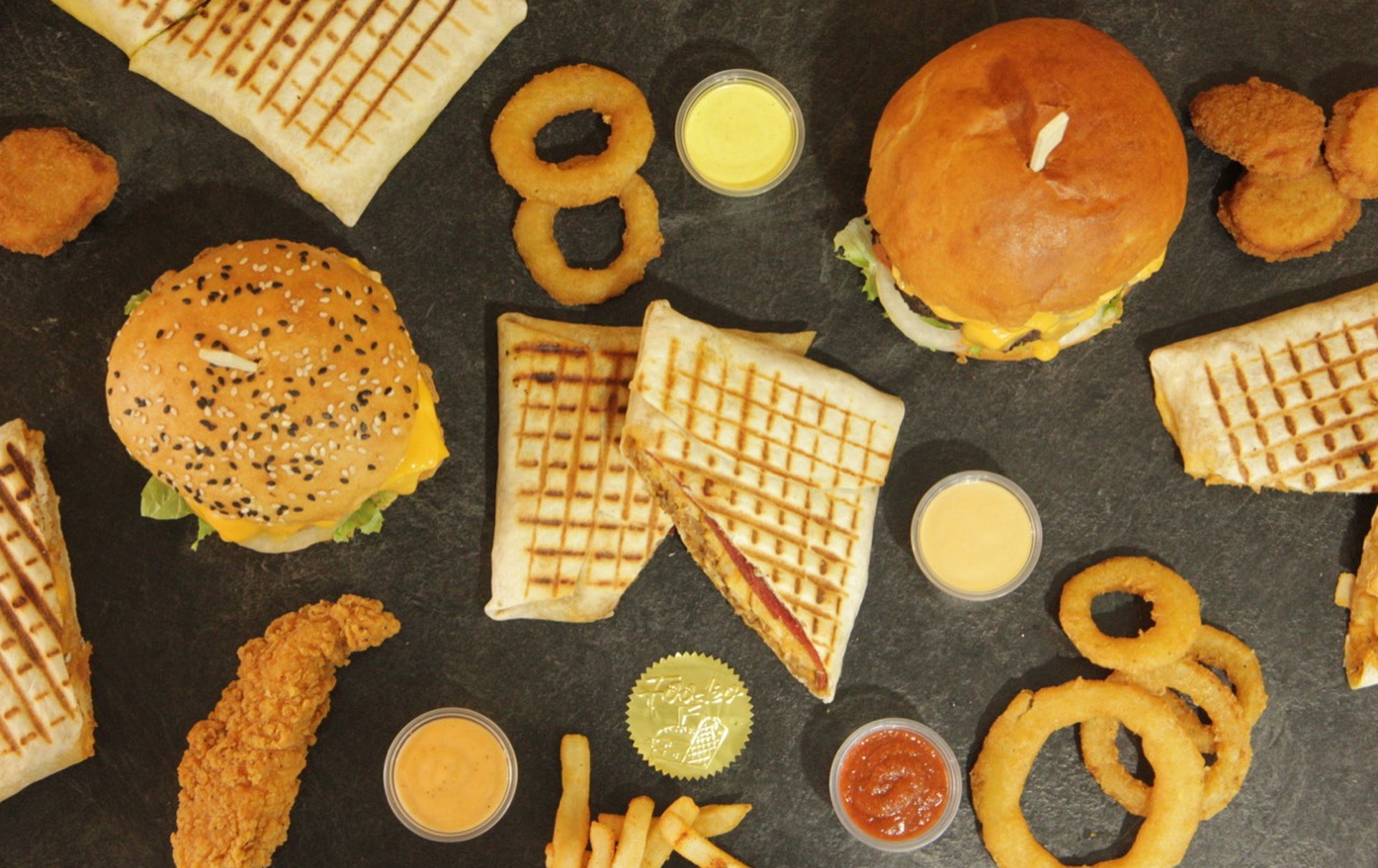 Menu Foodéo vu du dessus avec burgers, tacos, rondelles et sauces maison